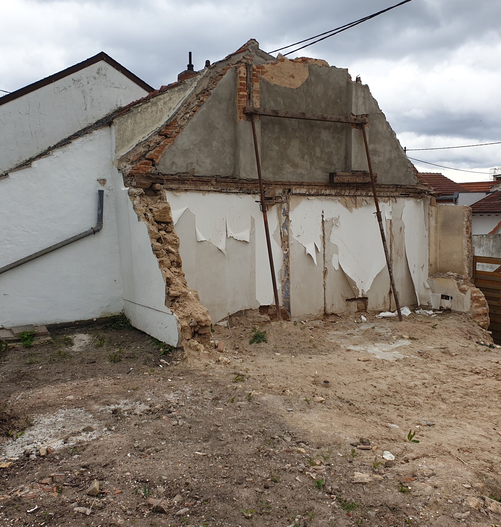 Verfallenes Haus mit bröckelnder Putzwand, maroden Stützbalken und Schutt im Hof.