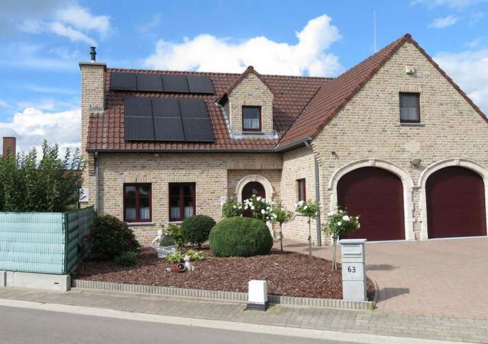 Zweistöckiges Backsteinhaus mit roten Dachziegeln, Solarzellen, gepflegtem Vorgarten und Doppelgarage Nr. 63
