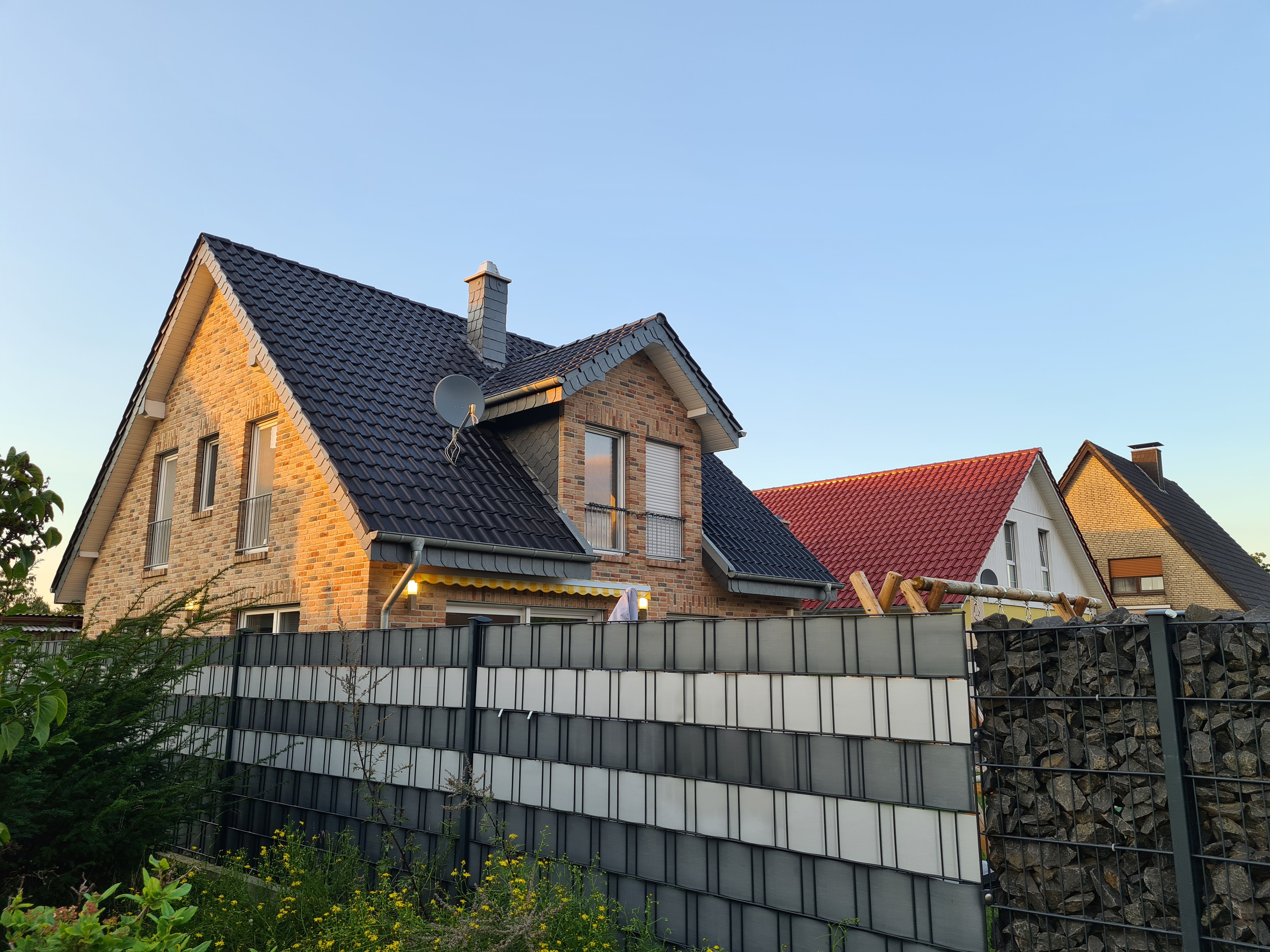 ziegelhaus-dunkelblaues-dach-aussenansicht-mit-zaun.jpg