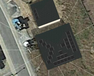 Luftbildaufnahme zeigt zwei Häuser mit dunklen Dächern und Solarzellen neben einer Straße