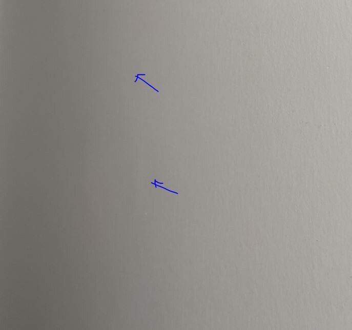 Zwei kleine blaue Striche an einer hellgrauen Wand.
