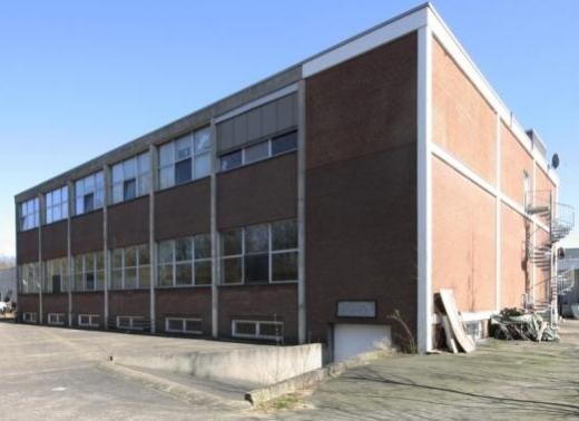 Zweistoeckiges Industriegebaeude aus rotem Backstein mit grossen Fenstern