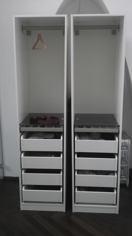 Zwei weisse Kleiderschraenke mit Kleiderstange und Schubladen im Schlafzimmer.