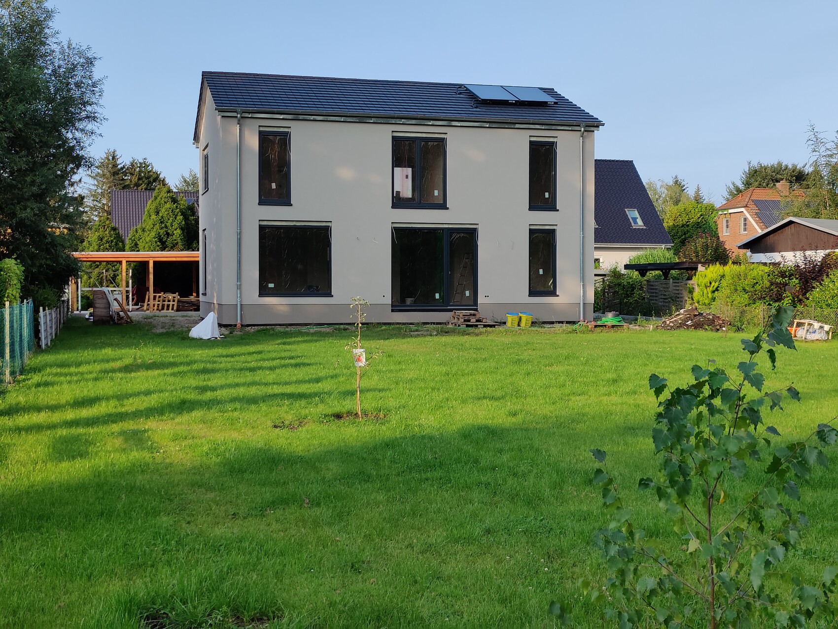 Zweistöckiges Haus im Bau mit grünem Garten und Bauarbeiten